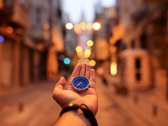 hand holding a blue compass to navigate in a city